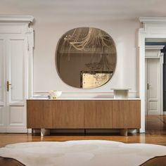 a living room with a large round mirror on the wall and wooden furniture in front of it