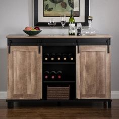 an entertainment center with wine bottles and glasses on it's cabinet doors, in front of a painting