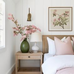 a bed room with a neatly made bed and two vases on the side table