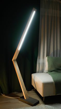 a lamp that is sitting on top of a floor next to a bed with a green blanket