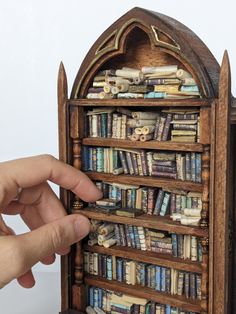 a hand is pointing at a book shelf made out of books