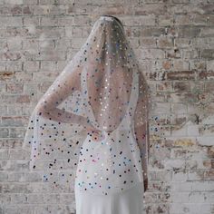 the back of a woman's white dress with multicolored dots on it