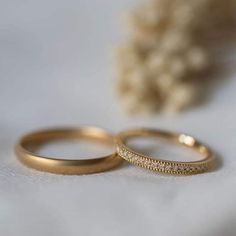 two gold wedding rings sitting next to each other