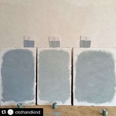 three different shades of gray paint sitting on top of a wooden table