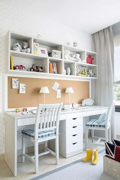 a white desk sitting under a window next to a wall mounted book shelf filled with books