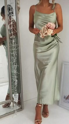 a woman standing in front of a mirror wearing a dress with flowers on the waist