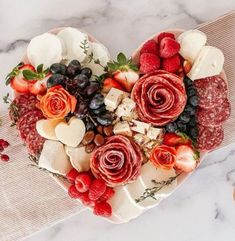 a heart shaped platter filled with cheese, fruit and meat for valentine's day