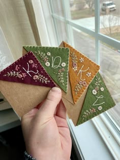 a person holding four small cards in front of a window