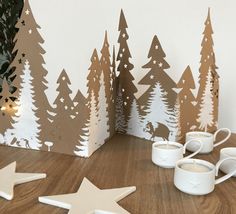 coffee cups and mugs are sitting on the floor next to paper cutout trees