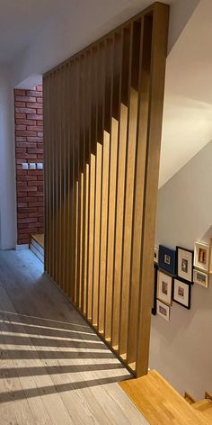 an empty room with wooden slats on the wall and framed pictures on the floor