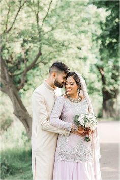 a bride and groom standing together in front of trees