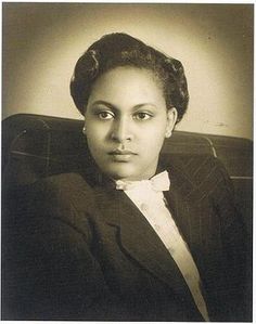 an old black and white photo of a woman in a suit with a bow tie