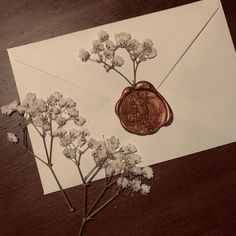 an envelope with a wax stamp and some flowers on the inside is laying on a table