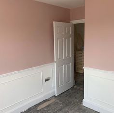 an empty room with pink walls and white trim on the door, carpeted floor