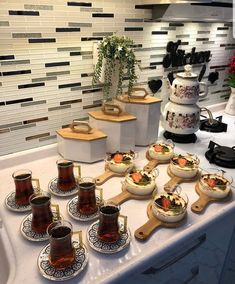 there are many cups and bowls on the kitchen counter with tea in front of them