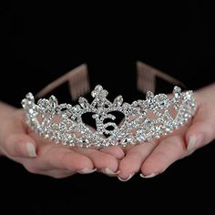 two hands holding a tiara in front of a black background with the word love written on it