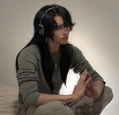 a woman sitting on top of a bed wearing headphones and holding her hands together