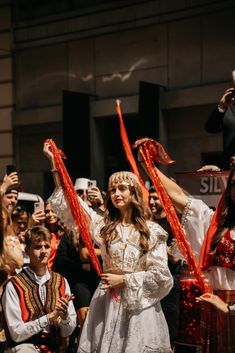 a group of people standing around each other in front of a crowd holding red streamers