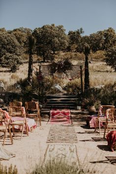 an outdoor ceremony setup with chairs and rugs