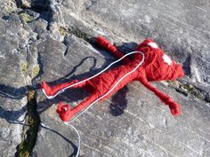 a red stuffed animal laying on top of a stone floor next to a pair of headphones