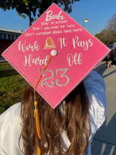 a girl wearing a pink graduation cap with writing on it that says work hard, play safe