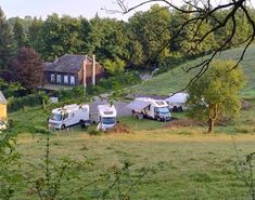 several campers are parked in a field next to a house