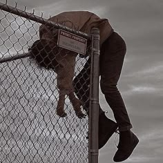 a person climbing up the side of a fence