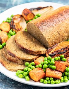 a white plate topped with meat, potatoes and peas