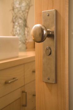 a door handle on the side of a wooden door in a bathroom with drawers and cabinets