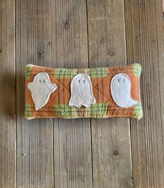 three ghost pillows sitting on top of a wooden floor