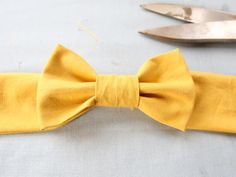 a yellow bow tie sitting on top of a table next to a pair of scissors