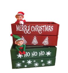 two elfs are sitting on top of boxes with merry christmas written on the sides