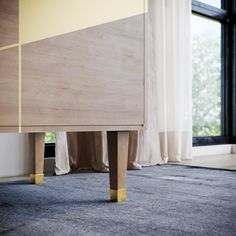 a wooden cabinet with two yellow legs in front of a window and curtains behind it