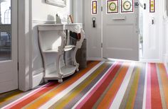 a hallway with striped carpeting and white door frames on the wall, next to a console table