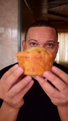 a man holding up a pastry in front of his face