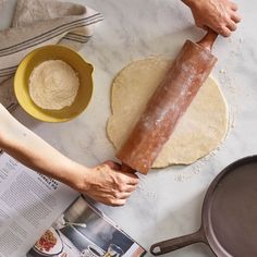 a person rolling dough on top of a table next to a pan and spatula