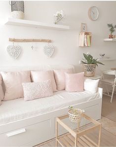 a living room with white furniture and lots of pink pillows on the back of the couch