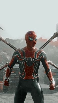 the spider - man is standing in front of some vehicles with his arms out and two swords