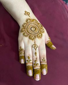 a woman's hand with hennap painted on it and gold decorations around the wrist