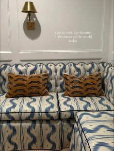 a blue and white couch sitting in front of a wall mounted clock with a quote on it