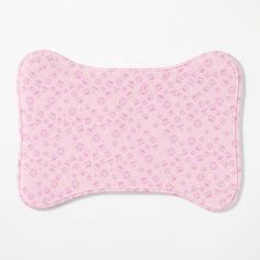 a pink dog bone shaped pillow with flowers and hearts on the front, against a white background