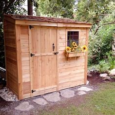 a wooden storage shed with sunflowers in the window