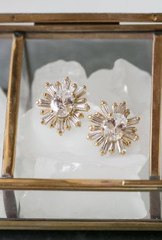 two pairs of diamond earrings sitting in a glass box