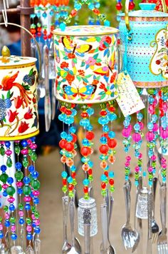 several colorful tin canisters with spoons and forks hanging from them