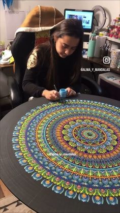 a woman sitting in front of a table with a large circular design on top of it