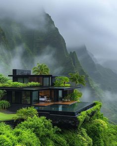 the house is surrounded by lush green trees and mountain side vegetation, with fog in the air