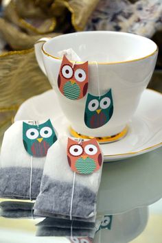 two owl tea towels sitting next to a cup and saucer