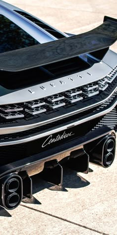 the front end of a black sports car with chrome lettering on it's hood