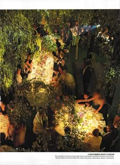 a group of people sitting around a table in the middle of a forest at night