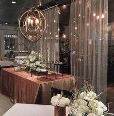 a table with flowers and candles on it in front of a glass wall that has sheer curtains